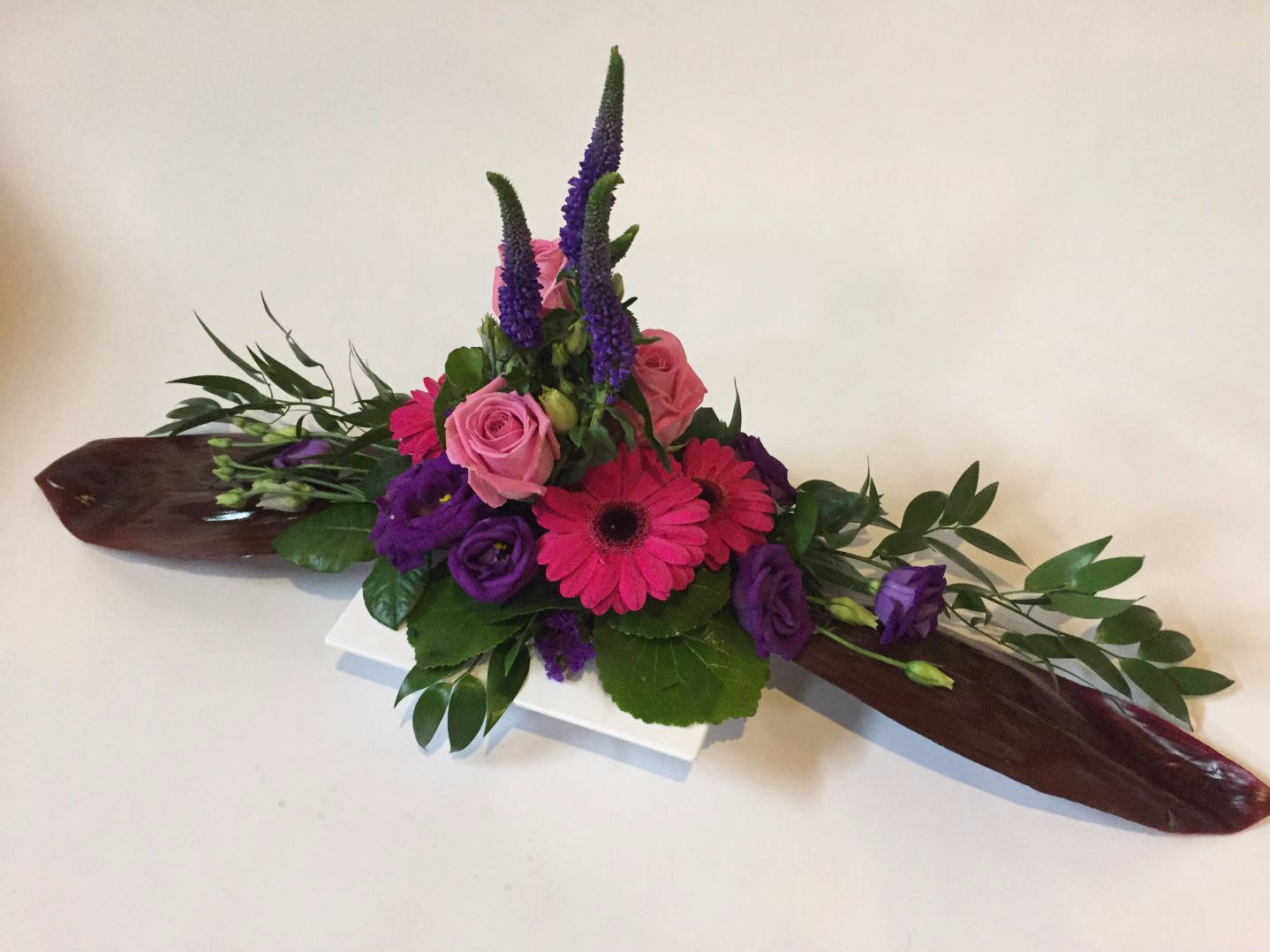 Langes Tischgesteck aus violetten und lila Blumen